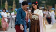 People dressed in traditional costumes look at a mobile phone at the Royal Plaza, as interest for historical clothing rises within the country, in Bangkok, Thailand April 6, 2018. Reuters/Soe Zeya Tun