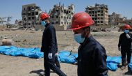 Syrians recovering bodies that have been found in a mass grave in the former Islamic State group stronghold of Raqa in Syria.  AFP / Delil souleiman
