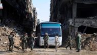 Soldiers loyal to Syria's President Bashar al Assad are seen near a bus carrying rebels from Yarmouk Palestinian camp in Damascus, Syria April 30, 2018. Picture Taken April 30, 2018. SANA
