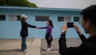 Visitors stand before a mock military demarcation line as they pose for photos at a replica of the DMZ border truce village of Panmunjom, built as a film set, near Namyangju, east of Seoul on May 5, 2018. AFP / Ed Jones