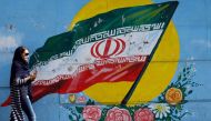 An Iranian woman walks past a mural of the Iranian flag in the capital Tehran on October 14, 2017. AFP