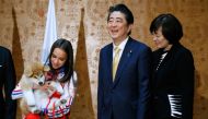 Russian figure skating gold medallist Alina Zagitova (L), Japanese Prime Minister Shinzo Abe (C) and his wife Akie Abe poses with an Akita Inu puppy presented to Zagitova in Moscow on May 26, 2018 during Abe's official visit to Russia. AFP / Alexander Zem