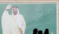 FILE PHOTO: Women walk past a poster of Saudi Arabia's King Salman bin Abdulaziz Al Saud during Janadriyah Cultural Festival on the outskirts of Riyadh, Saudi Arabia February 12, 2018. REUTERS/Faisal Al Nasser