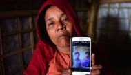 Rohingya Muslim refugee Khadija Begum, the mother of 16-year-old Rohingya youth Robi Alam, shows a photograph of two of her other sons during an interview with AFP at their house in Kutapalong refugee camp in Bangladesh's Cox's Bazar district. AFP / Munir