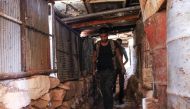 Moawiya Sayasina, the Syrian activist who started scribbling anti-Assad slogans in 2011, walks through a trench carrying a Kalashnikov assault rifle at a fortified position near the frontline in a rebel-held neighbourhood in the southern Syrian city of Da