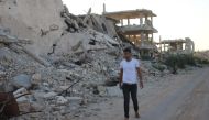 FILE PHOTO. Moawiya Sayasina, the Syrian activist who started scribbling anti-Assad slogans in 2011, walks past the rubble of destroyed buildings in a rebel-held neighbourhood in the southern Syrian city of Daraa on June 5, 2018. AFP / Mohamad ABAZEED
