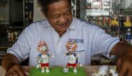 This picture taken on June 20, 2018 shows retired Vietnamese English teacher Nguyen Thanh Tam displaying two finished models of Zabivaka (L), the 2018 Russian World Cup mascot, made from eggshells, at his home in Ho Chi Minh City.  / AFP / Thanh NGUYEN