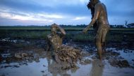 Devotees wearing costumes made of banana leaves cover themselves with mud as they prepare to head to church to attend a mass as part of a religious festival. AFP / NOEL CELIS