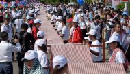 Cambodians roll out a 1,149.8 metre-long krama scarf so it can be declared as the world's longest hand woven scarf, in Phnom Penh on July 1, 2018. AFP / Tang Chhin Sothy

