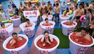 Participants take a bath in barrels filled with chilli peppers during the Spicy Barrel Challenge contest inside a water park in Chongqing, China July 7, 2018. Chen Chao/CNS via Reuters