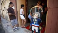 In this file photo taken on July 25, 2018 a woman with kids enters the Naporama museum, deficting Napoleon Bonaparte's life with playmobils in Ajaccio on the French Mediterranean island of Corsica. AFP / Pascal Pochard-Casabianca
 