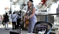 Busker Charlotte Campbell, who uses a contactless card reader for donations in addition to cash, performs near the London Eye in central London on September 1, 2018. AFP / Daniel Leal-Olivas 