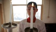 An altar boy holds a candle in preparation for the Palm Sunday procession held by a government-sanctioned Catholic church in Youtong village, Hebei province, China, March 25, 2018. Reuters/Damir Sagolj 