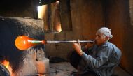 In this photo taken on August 2, 2018, Afghan man glassblower Ghulam Sakhi, mid-40s, crafts a glass object at his traditional glassblowing workshop in Herat province. AFP / HOSHANG HASHIMI 