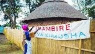 Poet, storyteller and retired schoolteacher, Hatifari Munongi adjusts a welcome banner reading at the replica traditional homestead she set up in the backyard of her house in the suburb of Marlborough in Harare on October 18, 2018.  AFP / Jekesai Njikizan