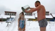 Grigory Broverman, a member of the Cryophile winter swimmers club, pours a bucket of cold water over his 9-year-old daughter Liza during a celebration of Polar Bear Day at the Royev Ruchey zoo, with the air temperature at about minus 5 degrees Celsius, in