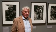 British photographer Don McCullin poses for a picture in front of his photographs including 'Shell-shocked US marine, the Battle of Hue 1968' (L), during a press preview of a retrospective exhibition of McCullin's work at Tate Britain in London on Februar