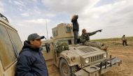 Paul Bradley (R), a volunteer with the Free Burma Rangers (FBR), sits on a US-made Humvee at a plateau overlooking the embattled Baghouz area in the eastern Syrian province of Deir Ezzor, on February 14, 2019. AFP / DELIL SOULEIMAN
