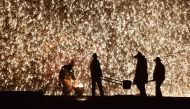 This photo taken on February 18, 2019 shows a Chinese blacksmith (L) throwing molten metal against a cold stone wall to create a shower of sparks, on the eve of the Lantern Festival, which marks the end of Lunar New Year celebrations, in Nuanquan, in Chin