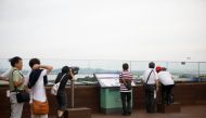 Visitors look toward a North Korean village through a pair of binoculars at a shopping mall near the demilitarized zone separating the two Koreas in Paju, July 16, 2017. Reuters/Kim Hong-Ji