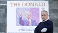 Painter Avni Delvina poses for a picture in front of a poster of his exhibition in the National Museum in Tirana, Albania, February 20, 2019. Reuters/Florion Goga 
 