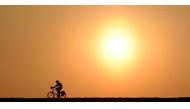 A cyclist passes a street near the village of Pflaumdorf, southern Germany, during sunset on February 28, 2019. AFP / Christof Stache 
 