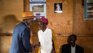 Jean-Bosco Gakwenzire (L), 65, of Tutsi ethnicity shakes the hand of Rose, 72, wife of his old school mate, Pascal Shyirahwamaboko (R), 68, both Hutu's, following Sunday mass at their church in the sector of Mutete, in Byumba city.  AFP / Jacques Nkinzing