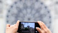 A man takes pictures of Notre-Dame Cathedral after a massive fire devastated large parts of the gothic gem in Paris, France April 16, 2019. Reuters/Gonzalo Fuentes