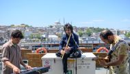 Musicians Oguzhan Erdem (C) plays ney, Eren Koc (L) keyboard and Zafer Saka(R) guitar during a ferry trip on the Bosphorus from Kadikoy to Eminonu, in Istanbul, on May 16, 2019. AFP / BULENT KILIC