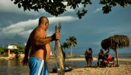 A man carries a fish at Mayabeque beach in Mayabeque province, Cuba, on July 4, 2019. AFP / Yamil Lage 