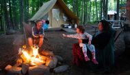 A family enjoys a campfire at the Huttopia Sutton glamping ground in Quebec, Canada, on August 14, 2019.  AFP / Sebastien St-Jean