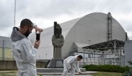 Tourists take pictures at New Safe Confinement (NSC), new metal dome encasing the destroyed reactor, at Chernobyl plant, Ukraine, on August 15, 2019. AFP / Genya Savilov 
