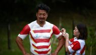 Hiroshi Moriyama (L) has his upper body painted by his wife Rika in the color of the Japanese team in front of the Ecopa Stadium in Shizuoka on September 28, 2019 during the Japan 2019 Rugby World Cup. AFP / Anne-Christine Poujoulat 