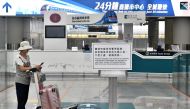 A woman stands next to a sign informing passengers the rail link between the airport and downtown is closed in Hong Kong on October 5, 2019, a day after the city's leader outlawed face coverings at protests invoking colonial-era emergency powers not used 