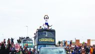 People cheer as South African Rugby captain Siya Kolisi (C) holds up the Web Ellis Trophy while the South African Rugby World Cup winner team parades on an open top bus through the streets of the city of Zwide , Port Elizabeth, on November 10, 2019. AFP /