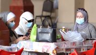 Kuwaiti women wear protective masks as they sit in a restaurant inside the Mubarakiya Market in Kuwait City on February 24, 2020. AFP / YASSER AL-ZAYYAT