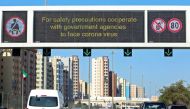 Vehicles pass by a billboard showing precautionary instructions against the COVID-19 coronavirus disease as they drive along a main highway in Kuwait City on March 3, 2020. / AFP / YASSER AL-ZAYYAT