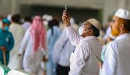 A worshipper wearing a protective mask, takes photographs around Mecca's Grand Mosque on March 6, 2020. AFP / Abdel Ghani BASHIR