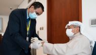 A bank security guard helps an elderly client to put protective gloves on before he enters the bank, following the outbreak of coronavirus, in Shaab, Kuwait March 15,2020.REUTERS/Stephanie McGehee