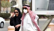 A Saudi man, wearing a protective mask as a precaution against COVID-19 coronavirus disease, walks with his wife along Tahlia street in the centre of the capital Riyadh on March 15, 2020. / AFP / FAYEZ NURELDINE