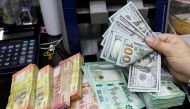 A man counts U.S. dollar banknotes next to Lebanese pounds at a currency exchange shop in Beirut, Lebanon April 24, 2020. REUTERS/Mohamed Azakir