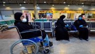 A wheelchair-bound woman waits with other Kuwaiti nationals for a repatriation flight at Najaf International Airport on May 5, 2020, after being quarantined at a hotel in Iraq's central holy shrine city of Najaf. / AFP / Haidar HAMDANI