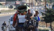 A displaced Syrian man drives his agricultural vehicle loaded with belongings as he flees along the M4 highway, in Ariha in the rebel-held northwestern Syrian province of Idlib, on June 8, 2020, heading north. / AFP / Abdulaziz KETAZ