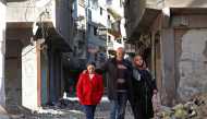 Issa al-Loubani, a 48-year-old Palestinian refugee, walks with his wife and daughter in a street in the Palestinian Yarmuk camp, on the southern outskirts of the Syrian capital Damascus, on November 25, 2020. AFP / LOUAI BESHARA