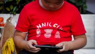 A boy plays a game on a phone on a street in Shanghai, China August 31, 2021. REUTERS/Aly Song