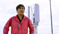 Challenergy's President and Chief Executive Atsushi Shimizu stand stands in front of the company's Magnus Vertical Axis Wind Turbine, which can work in cyclonic conditions, in Ishigaki on Japanese southern island of Ishigaki, Okinawa prefecture, November 