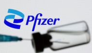 A syringe and vial are seen in front of a displayed Pfizer logo in this illustration taken June 24, 2021. REUTERS/Dado Ruvic/Illustration/File Photo