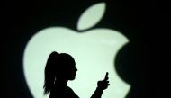 Silhouette of mobile user is seen next to a screen projection of Apple logo in this picture illustration taken March 28, 2018. REUTERS/Dado Ruvic/Illustration/File Photo