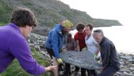 Researchers carry part of the fossil of a newly identified Jurassic Period flying reptile, or pterosaur, called 'Dearc sgiathanach', found on a rocky beach at Scotland's Isle of Skye, Britain in this handout image from May 2017. Shasta Marrero/Handout via Reuters