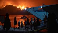 People board a ferry during evacuation as a wildfire burns in the village of Limni, on the island of Evia, Greece, August 6, 2021. REUTERS/Nicolas Economou/File Photo
 